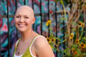 Bald woman with cancer in front of graffiti wall