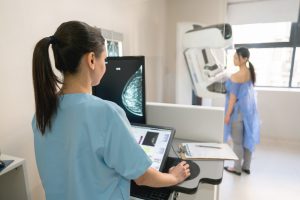 Technologist performing a mammogram on a screening client